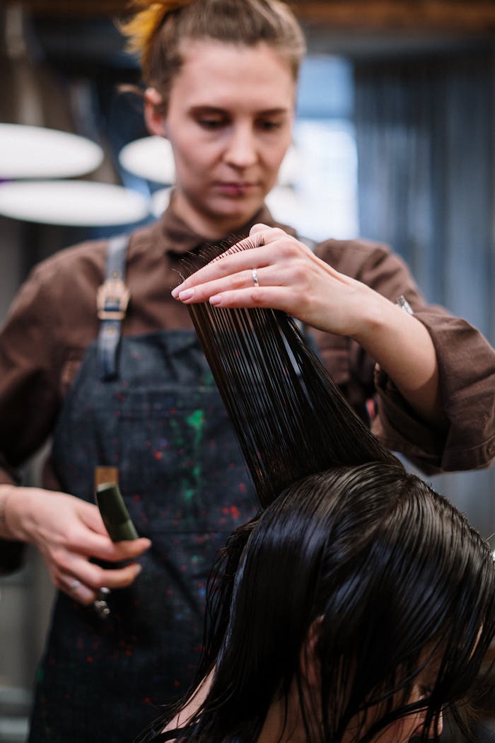 Expert stylist cutting client's wet hair in a stylish salon setting.