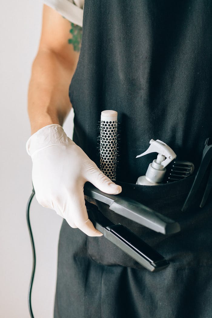 Hairdresser’s apron with tools like a brush and flat iron, showcasing hairstylist essentials.